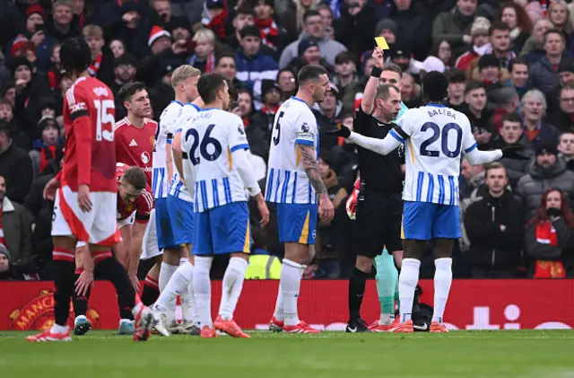 Referee Peter Bankes shows a yellow card to Carlos Baleba