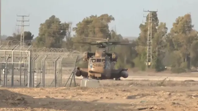 Israeli Air Force helicopter lands in designated reception location on outskirts of the Re'im kibbutz in southern Israel. Trees and shrubbery visible in the background