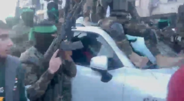 A Red Cross vehicle shows Hamas gunman on the bonnet of the car