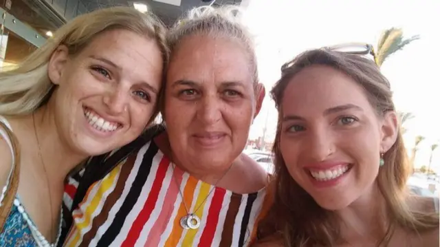 Doron, her mother Simona, and her sister Yamit Ashkenazi smiling at the camera taking a selfie outdoors, all three dressed in summer clothing