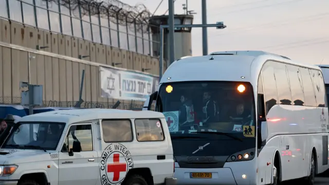 Two Red Cross vehicles outside the prison wall