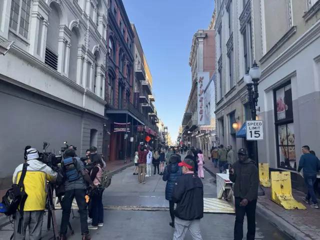 Reporters and pedestrians standing on Bourbon Street