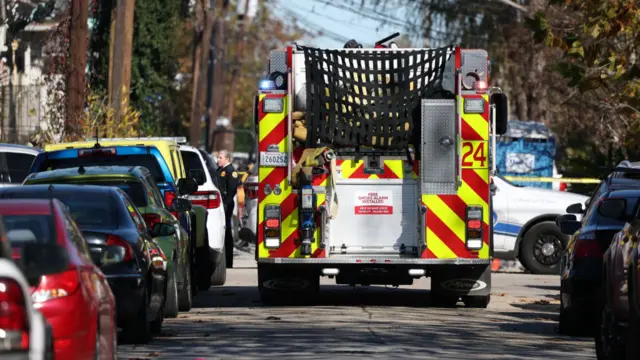 A fire truck is pictured in the middle of a street with a line of cars on either side.