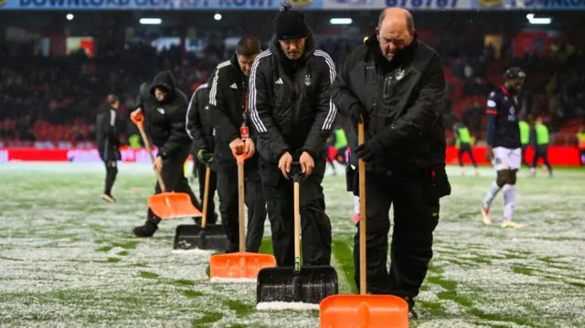 Aberdeen ground staff clear the pitch of snow