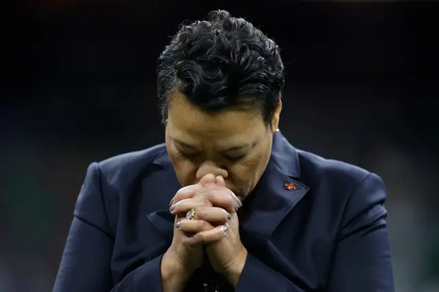 LaToya Cantrell with her head down and hands clasped together, in a prayer like position