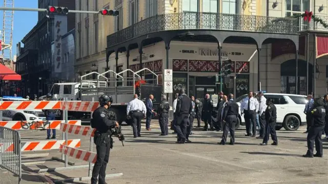 Police and officials walk down a barricaded Bourbon Street