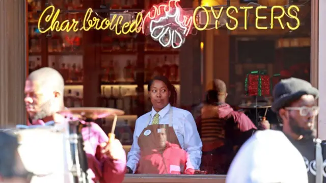 A server watches the brass band play outside