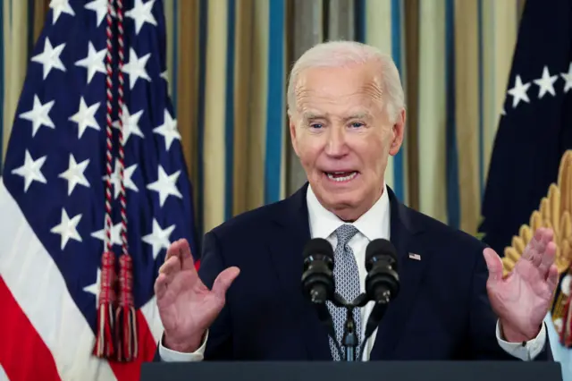 President Biden speaking at a lectern with the US flag behind him