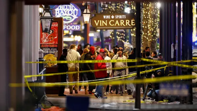 People stand near the site where people were killed by a man driving a truck in an attack during New Year's celebrations, in New Orleans