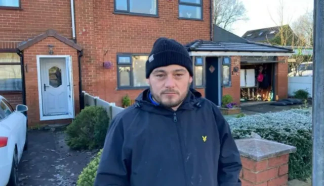 Daniel Pownall stands in front of his flooded home