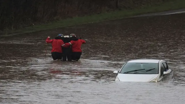 Firefighters rescue a man from his car, after he became trapped in flood water on the A555 near Bramhall