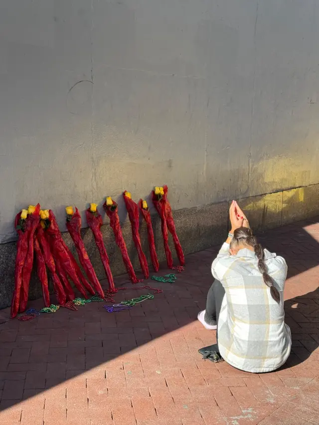 Woman kneels at New Orleans memorial display