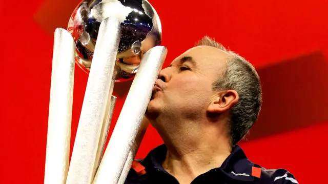 Phil Taylor kisses the World Championship trophy