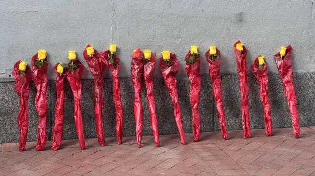 14 yellow flowers standing up against a wall on Bourbon street