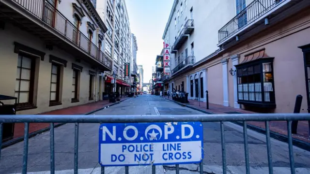 A NOOPD sign on a fence blocks a street and reads: "Police line do not cross"