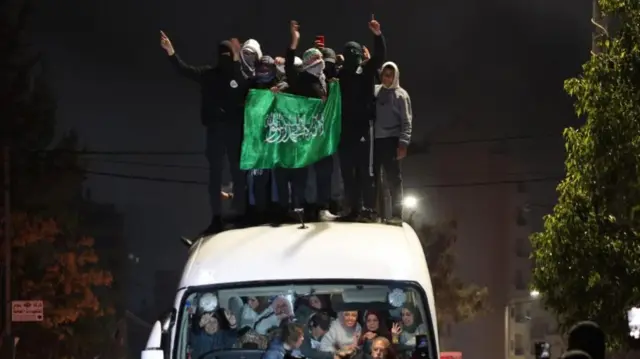 Group men standing on top of bus, celebrating, with women inside bus smiling