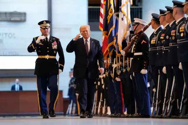 President Donald Trump salutes soldiers standing in a row in the US Capitol visitor centre.