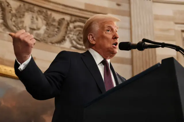 President Donald Trump speaks during inauguration ceremonies in the Rotunda. He sticks a thumb out as he speaks