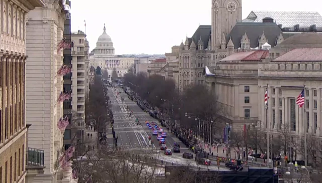 A street view zoomed out, with several police cars flashing lights and people stood by