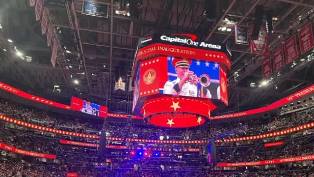 Wide shot of seated crowd in the Capital One Arena with a large screen in the middle