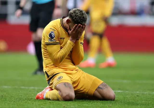 Cunha covers his face with his fans as he kneels on the floor after missing a good chance