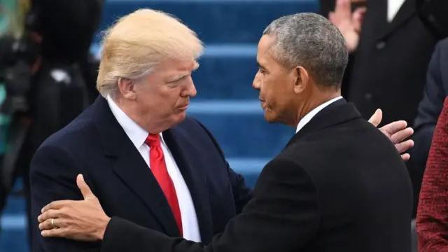 Trump and Obama shake hands, each reaching out with their other hand to embrace the other