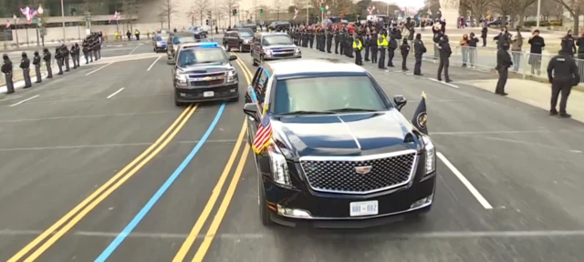 President's black car on a road with several cars behind it