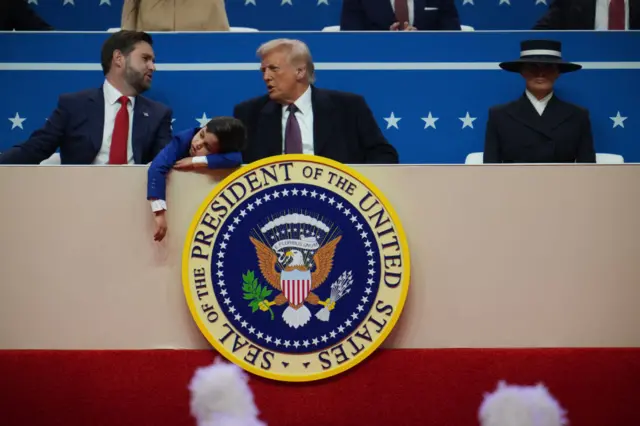 The arm of JD Vance's son hangs off the stage while Trump and Vance speak