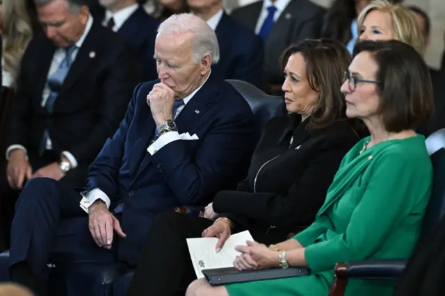 Former US President Joe Biden and former Vice President Kamala Harris look on as Donald Trump delivers remarks