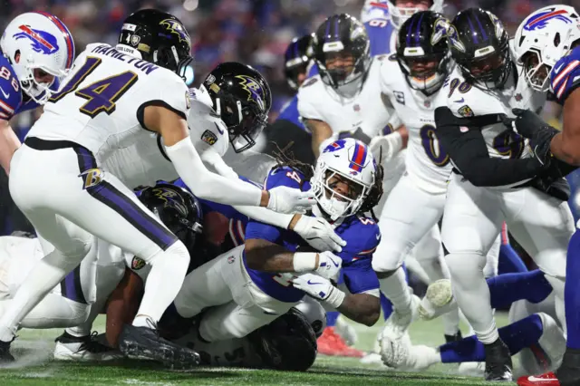 Baltimore Ravens defenders tackle James Cook