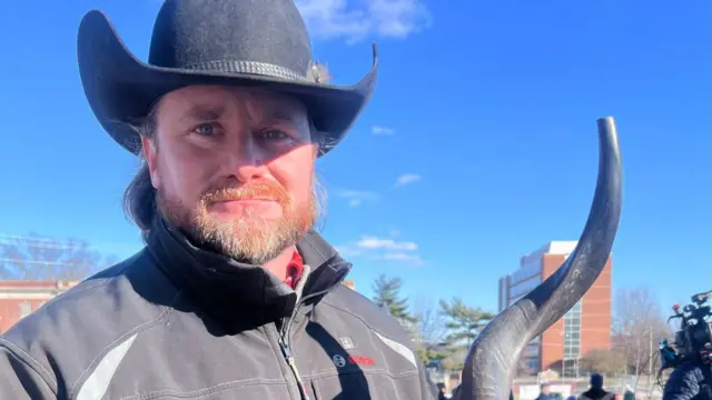 James Charles Phillips carrying a ram's horn and wearing cowboy hat