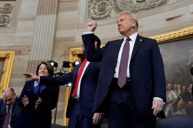 Trump clenches his fist and raises it to the air in the Capitol Rotunda