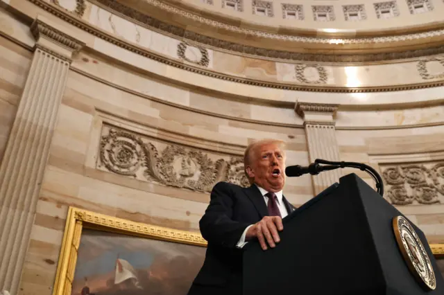 Trump speaking into a microphone in the fancy looking rotunda room