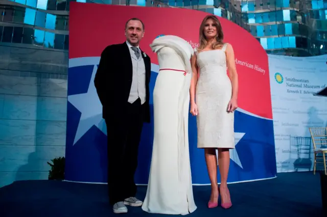 US First Lady Melania Trump stands alongside the gown she wore to the 2017 inaugural balls, and the gown's designer, Herve Pierre