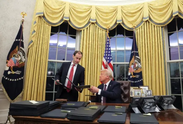 Man hands Trump a black folder