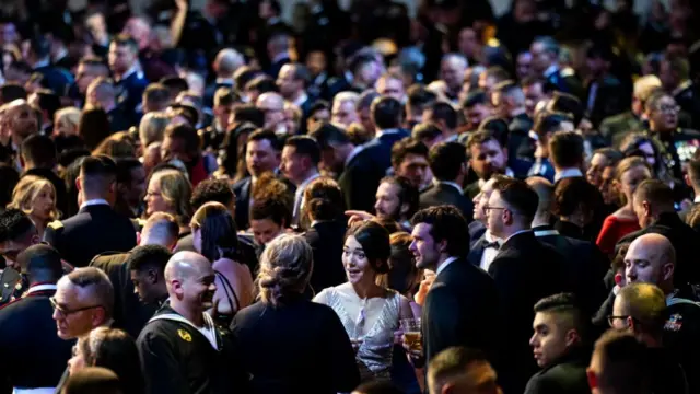 A crowd of guests mingle in a hall