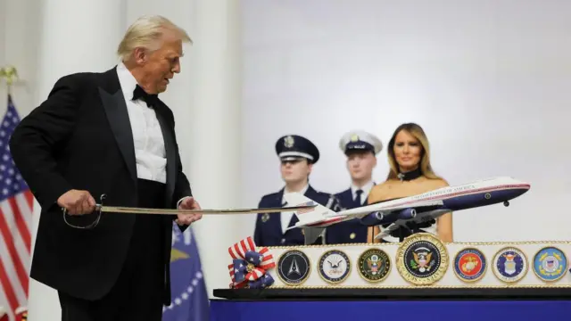 Donald Trump wearing a tuxedo suit, cutting an airplane cake using a sword