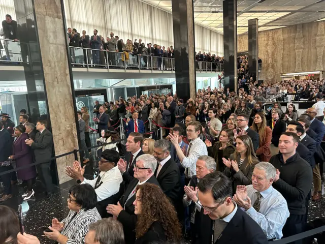 Crowd of State Department employees on two levels applaud