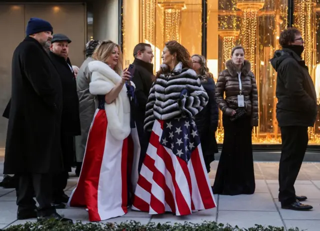 Two women wearing ballgowns featuring the US flag design line up to enter the Liberty inauguration ball in Washington, DC