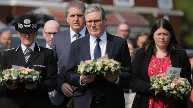 Keir Starmer carries a wreath in Southport