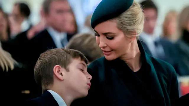 Ivanka Trump dressed in green watching her son sleep on her shoulder