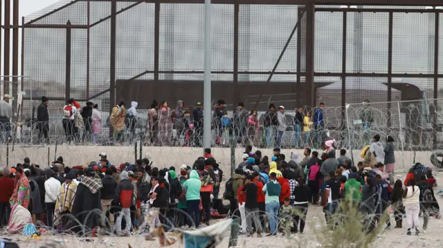 Migrants queue at the border fence to try to cross into the US, in Ciudad Juarez Chihuahua, Mexico, 19 December 2023