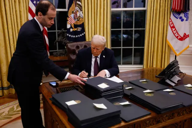 Trump with desk full of executive actions