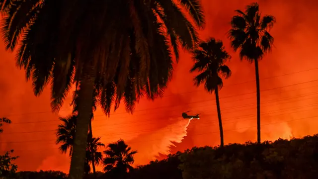 Firefighting planes and helicopters drop water over flames in Mandeville Canyon during 'Palisades Fire' in Los Angeles, California, United States on January 10, 2025