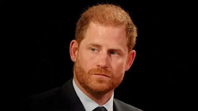 Prince Harry in a suit against a black background