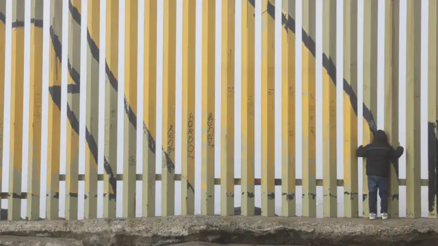 A person looks through a gap along the US-Mexico border wall in Tijuana, Mexico, 18 December 2024.