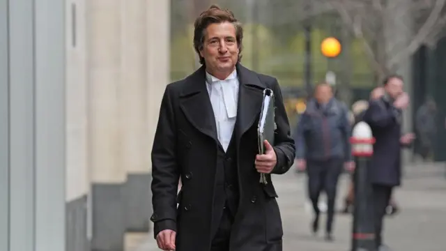 David Sherbourne in long black coat and white shirt outside High Court