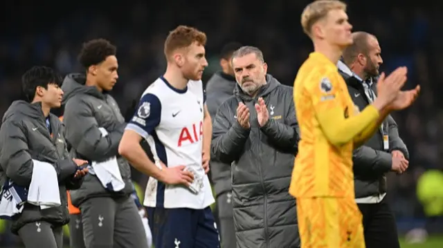 Ange Postecoglou looks on surrounded by Tottenham players