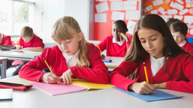 Students writing in classroom - stock photo