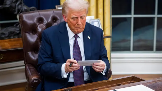 US President Donald Trump looks at a letter from former President Joe Biden left for him in the drawer of the Resolute desk on the first day of his presidency in the Oval Office of the White House